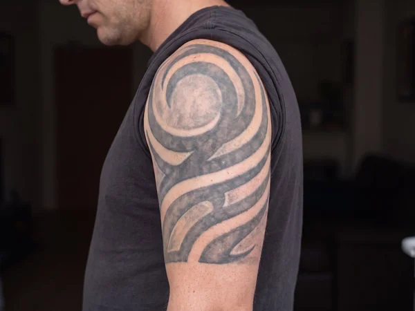 Partially faded dense black tribal shoulder tattoo ready for cover-up work